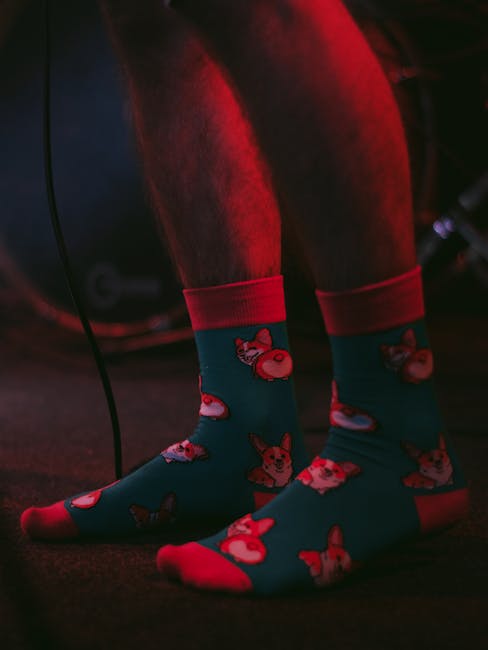 pexels-photo-8950116-8950116 Vibrant dog-themed socks under dramatic red lighting on a dark background.